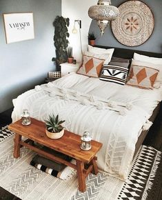 a bed sitting in a bedroom next to a wooden table with two potted plants on it