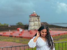 a woman in white dress standing next to a fence