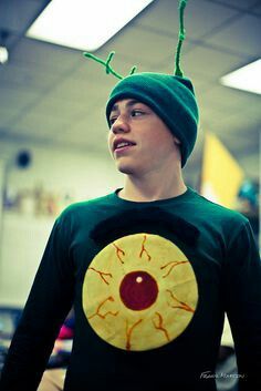 a young man wearing a green hat with a yellow circle on it