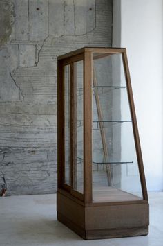 a wooden display case sitting on top of a white floor next to a brick wall