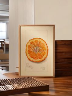 an orange cut in half sitting on top of a wooden table next to a computer keyboard