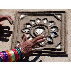 an old woman's hand reaching for something on the ground in front of a manhole cover