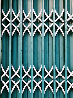 the metal fence is painted green and has white crosses on it, along with other patterns