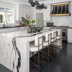 a large kitchen with marble counter tops and white chairs in front of an island that has four stools