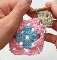 someone is crocheting a flower with yarn on the end of a knitting needle