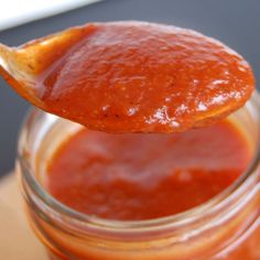 a wooden spoon full of sauce on top of a jar