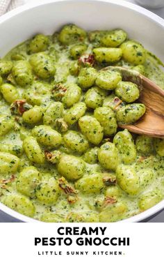 a white bowl filled with pesto gnocchini and a wooden spoon in it