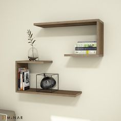 two black floating shelves on the wall above a bed with a vase and bookshelf