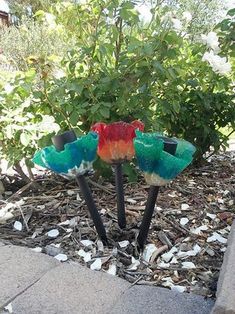 there are three colorful flowers in the middle of this yard, and one is made out of plastic cups