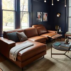 a living room with blue walls and leather couches in the corner, along with two windows