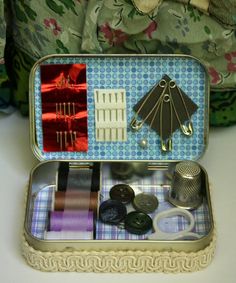 an open tin box with sewing supplies in it