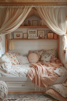 a white bed sitting under a window next to a wooden shelf filled with pillows and blankets