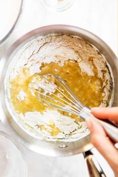 someone mixing ingredients in a bowl with a whisk