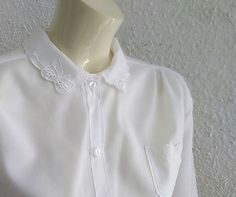 70s does 50s embroidered blouse sheer minimalist blouse ribbon embroidery collar feminine romantic blouse delicate simple elegant blouse Materials: minimalist delicate blouse, ribbon embroidered collar 70s does 50s embroidered blouse, sheer minimalist blouse, ribbon embroidery on collar and on the small chest pocket, feminine romantic blouse, delicate simple elegant blouse, polyester. Made in England. Measurements laying flat : shoulders :44cm (17,5 inches) bust:60 cm (23,5 inches) total lenght White Collared Feminine Blouse, Elegant Shirt With Lace Collar For Spring, Elegant White Shirt With Lace Collar, Elegant Collared Top With Floral Embroidery, Elegant Floral Embroidered Summer Shirt, Elegant White Shirt With Floral Embroidery, Elegant Embroidered Summer Shirt, Delicate Tops For Spring Wedding, Elegant Embroidered Blouse With Peter Pan Collar