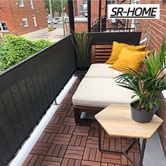 a small balcony with two couches and a coffee table on the floor next to a brick wall