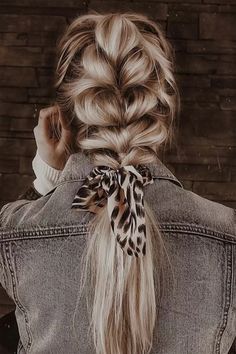 a woman with long blonde hair wearing a leopard print pony tail braid and denim jacket