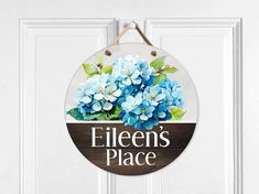 a wooden sign that says ellen's place with blue flowers hanging from the front door