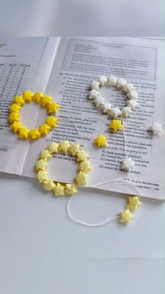 some yellow and white stars are laying on top of an open book with string attached to it