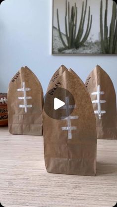 three brown paper bags with footballs on them sitting on top of a wooden table