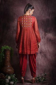 Brick red closed neck A line front pleated top with scattered metallic embellishments and gathered hem. Paired with dhoti pant.
Components: 2
Pattern: Embroidery
Type Of Work: Sequin, Beads, Thread Work
Neckline: Closed Round Neck
Sleeve Type: Full Flounced Sleeves
Fabric: Silk tissue , Viscose silk and Lining: Cotton
Color: Red
Other Details: 
Multicolour thread embroidery at neck and sleeve hem
Length:
Kurta(in inches): 33        
  Dhoti(in inches): 37


Occasion: Sangeet, Mehendi and Haldi - Embellished Palazzo Set For Navratri, Red Salwar Kameez With Dori Work, Red Dori Work Salwar Kameez, Navratri Embellished Salwar Kameez, Dhoti Pants, Pant For Women, Pleated Top, Pleat Top, Pattern Embroidery