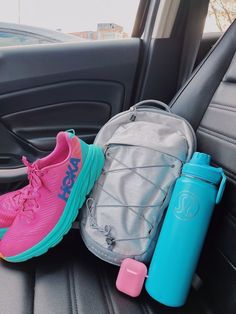 the back seat of a car with two water bottles, a backpack and a pair of running shoes