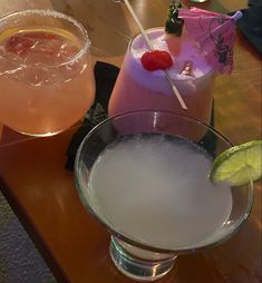 two cocktails are sitting on a table next to each other