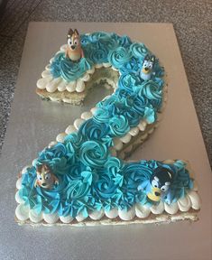 the number two cake is decorated with blue frosting and cartoon character figures on it