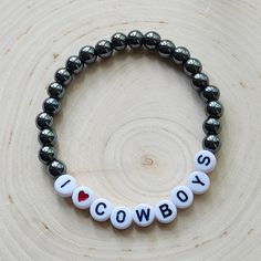 Plated Hematite beads and white plastic letter beads stating: I♡COWBOYS  Approximately 7 inches in length. This fun stretch bracelet is a great way to show off your love of all things country.  Makes a great gift for the cowboy lover. All bracelets are shipped in organza drawstring bags and boxed. >>S H I P P I N G details<< ✔️Ships in 1-2 days Country Beaded Bracelets, Country Bracelets Diy, Novelty White Stretch Bracelet With Round Beads, White Novelty Stretch Bracelet With Round Beads, Zach Bryan Bracelet Ideas, Western Bracelet Ideas, Country Clay Bead Bracelet Ideas, Country Bracelets, Beaded Letter Bracelets