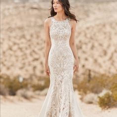 a woman standing in the sand wearing a wedding dress with an open back and lace detailing