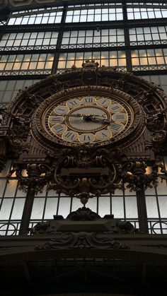 a large ornate clock mounted to the side of a building's glass window wall