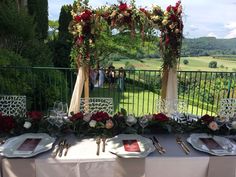 a table set up with place settings and flowers on it for an outdoor wedding reception