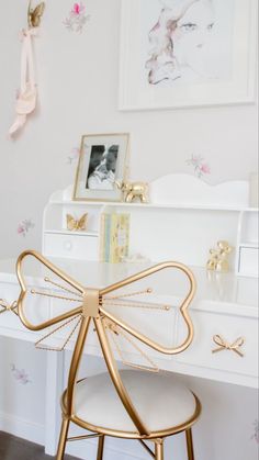 a white desk with a gold bow on it's top and some pictures above it