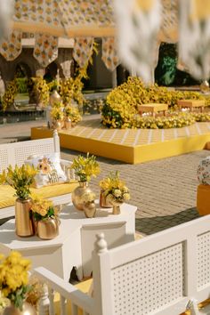 tables and chairs with flowers on them in front of a yellow tiled area that looks like a garden