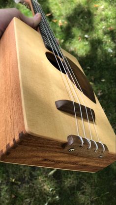 a close up of a person holding a guitar in their hand with trees in the background