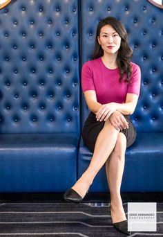 a woman sitting on top of a blue couch in front of a wall with circles