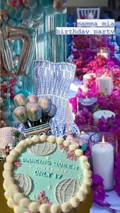 a birthday cake sitting on top of a table covered in balloons and flowers next to candles