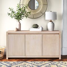 a living room with a rug, mirror and vases on the sideboard in front of it