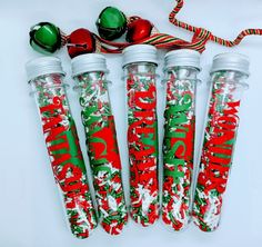 four christmas candy tubes are lined up next to each other on a white surface with red and green decorations