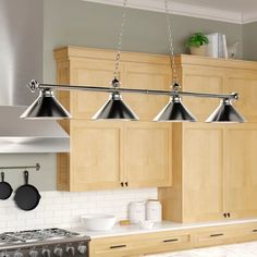 a kitchen with wooden cabinets and three lights hanging from the ceiling over the stove top