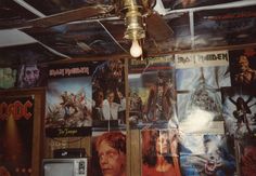 a room with posters on the wall and a ceiling fan hanging from it's ceiling