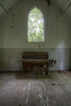 an old church with a stained glass window and wooden bench in the middle of it