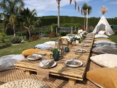 a picnic table set up with plates and silverware on it, surrounded by palm trees