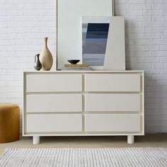 a white dresser sitting in front of a brick wall