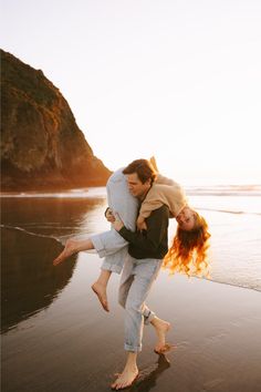 a man carrying a woman on his back as they walk along the beach at sunset