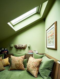 a green couch with pillows on it under a skylight