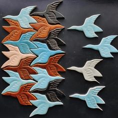 several different colored birds are flying in the air on a black surface with white and brown accents