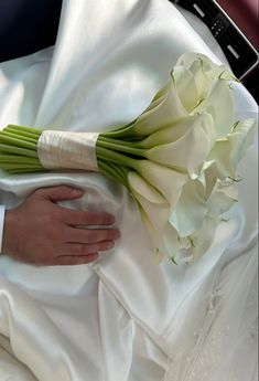 the bride's bouquet is wrapped in white satin and held by her grooms hand