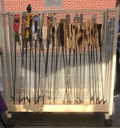 a rack with many pairs of skis on it next to a brick wall and sidewalk