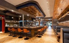 an empty bar with orange chairs and wooden flooring in a large open space area