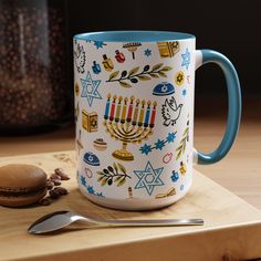 a coffee mug with hanukkah symbols on it next to a spoon and cookie